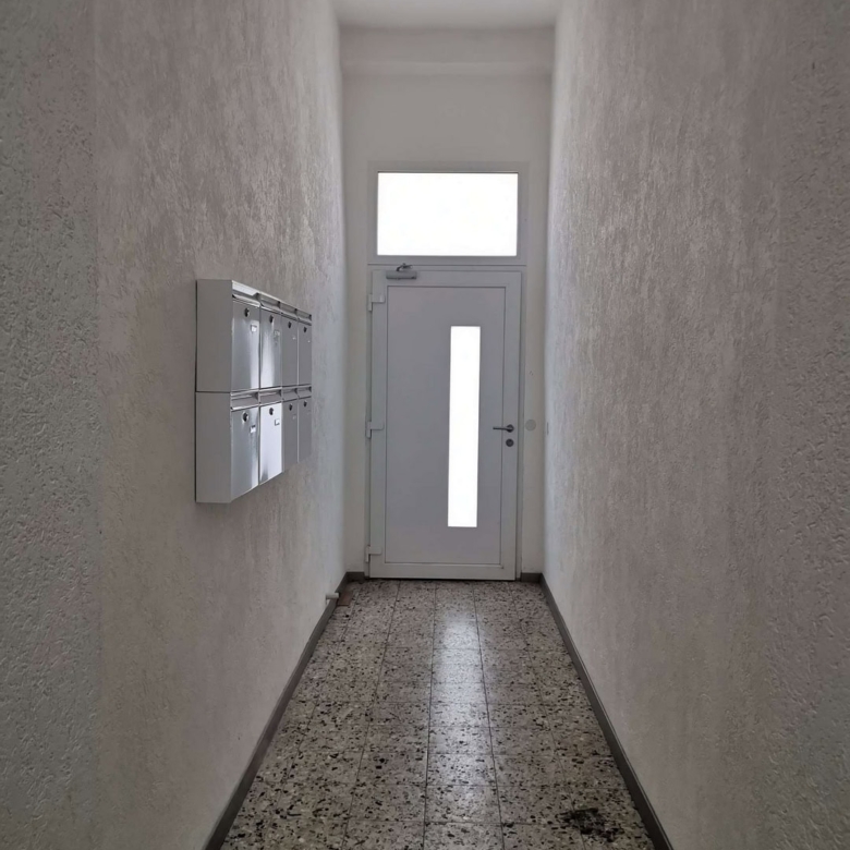Eingangsflur mit Briefkästen und weißer Tür, Flurgestaltung für Mehrfamilienhäuser, moderner Hausflur, gepflegte Flurgestaltung, DEM GROUP.