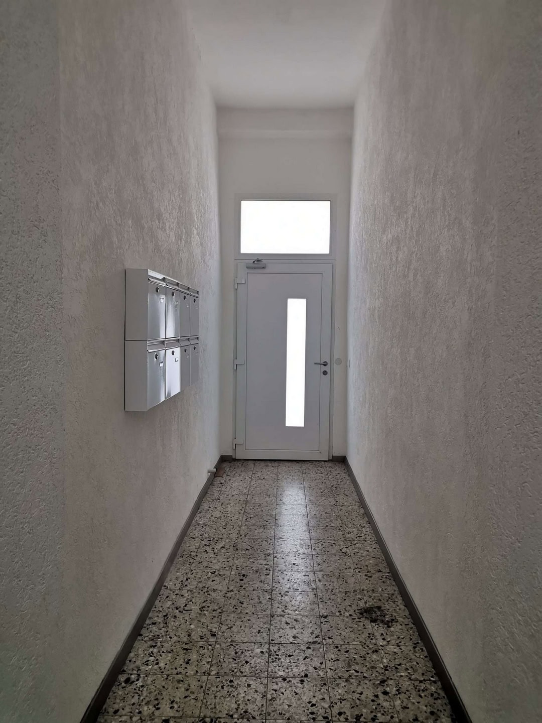 Eingangsflur mit Briefkästen und weißer Tür, Flurgestaltung für Mehrfamilienhäuser, moderner Hausflur, gepflegte Flurgestaltung, DEM GROUP.