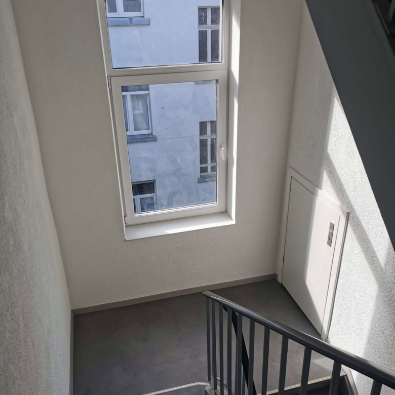 Moderne Treppenhaus mit Fenster, helle Wände, sichere Geländer, attraktive Raumgestaltung, hochwertiger Innenausbau.