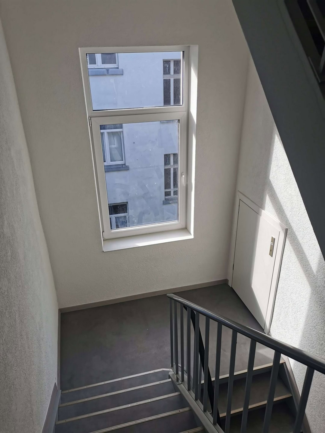 Moderne Treppenhaus mit Fenster, helle Wände, sichere Geländer, attraktive Raumgestaltung, hochwertiger Innenausbau.