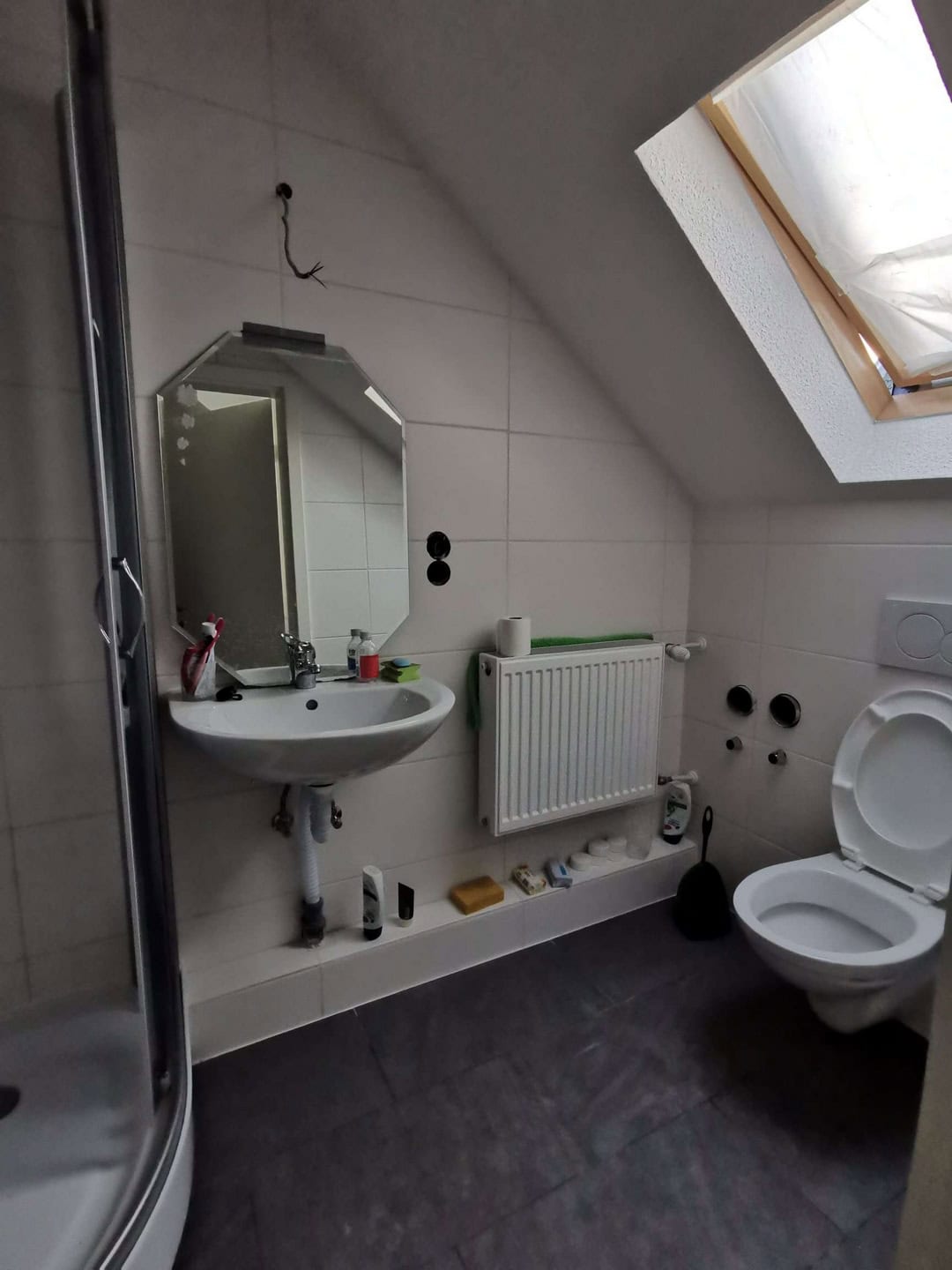 Moderne Badezimmergestaltung mit weißer Wandfliese, Dachfenster und komfortabler Toilette.