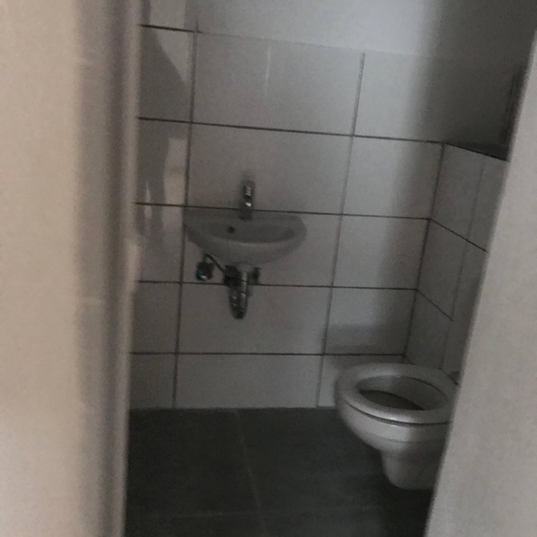 Sauberes kleines Toilettenraum mit Bidet und Waschbecken in modernen Fliesen.