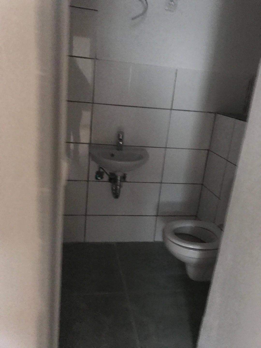 Sauberes kleines Toilettenraum mit Bidet und Waschbecken in modernen Fliesen.