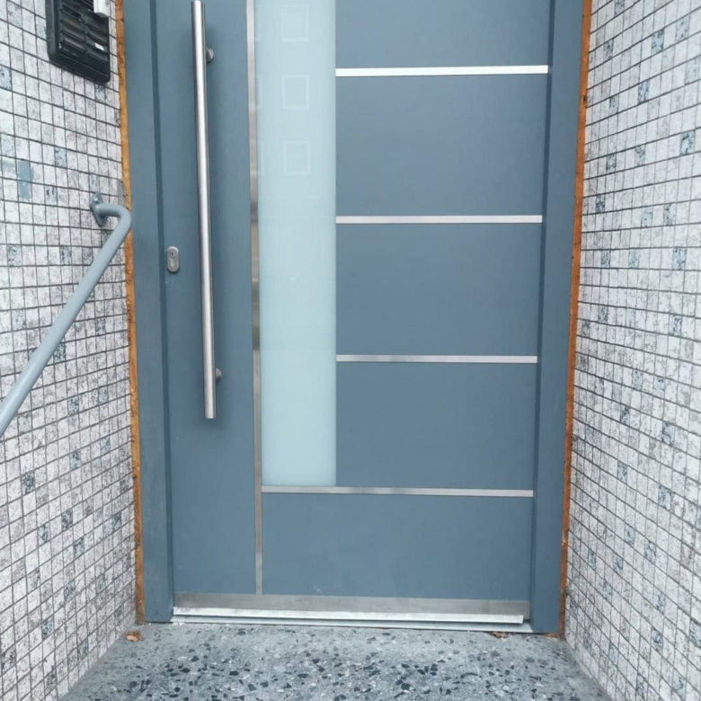 Modernes Haustürdesign aus Edelstahl mit klaren Linien und Sicherheitsmerkmalen.