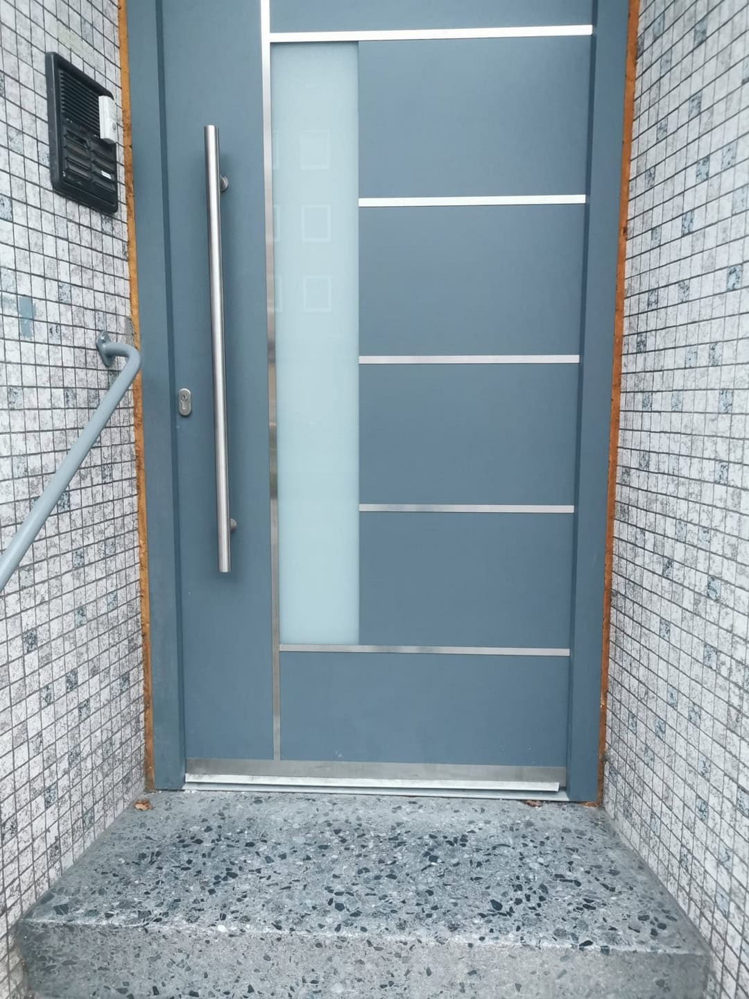 Modernes Haustürdesign aus Edelstahl mit klaren Linien und Sicherheitsmerkmalen.