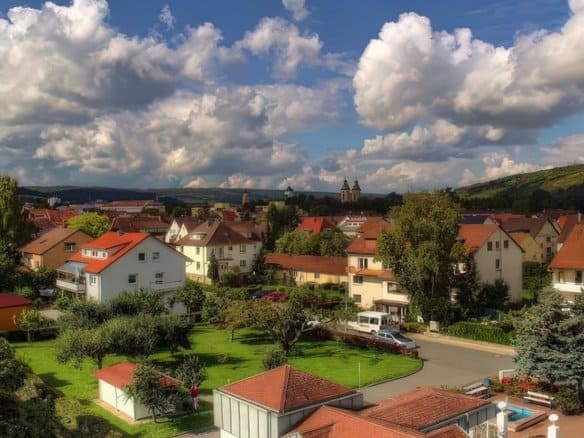 Разнообразные жилые дома в благоустроенном, зеленом жилом районе Германии, окруженные деревьями и гармоничной природой, для устойчивого жилья и высокого качества жизни.