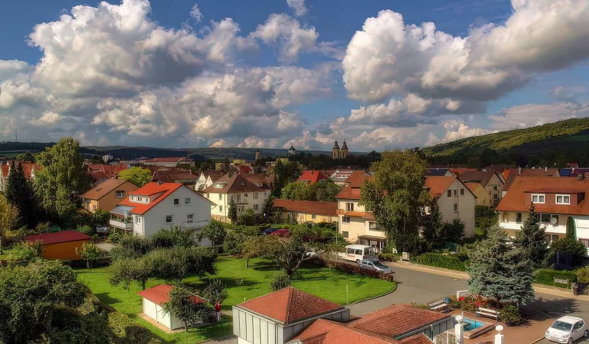 Diverse residential buildings in a well-maintained, green residential area in Germany, surrounded by trees and harmonious nature, for a sustainable home and quality of life.