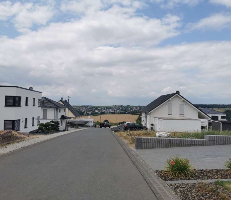 Moderne Wohnhäuser in einer Vorstadt, gepflegter Straßenabschnitt mit Haus- und Gartengestaltung, grüner Landschaftsausblick, ideal für Immobilien- und Bauunternehmen, DEM GROUP.
