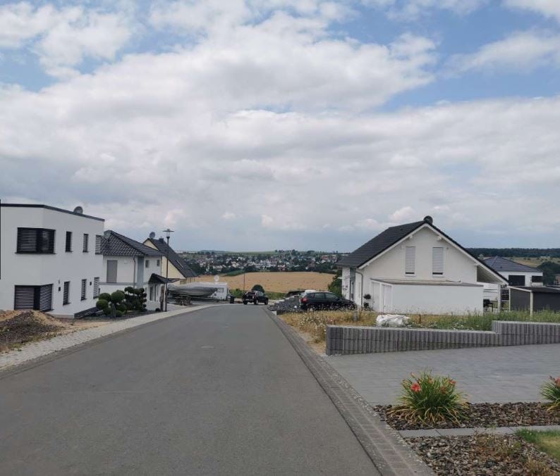 Moderne Wohnhäuser in einer Vorstadt, gepflegter Straßenabschnitt mit Haus- und Gartengestaltung, grüner Landschaftsausblick, ideal für Immobilien- und Bauunternehmen, DEM GROUP.