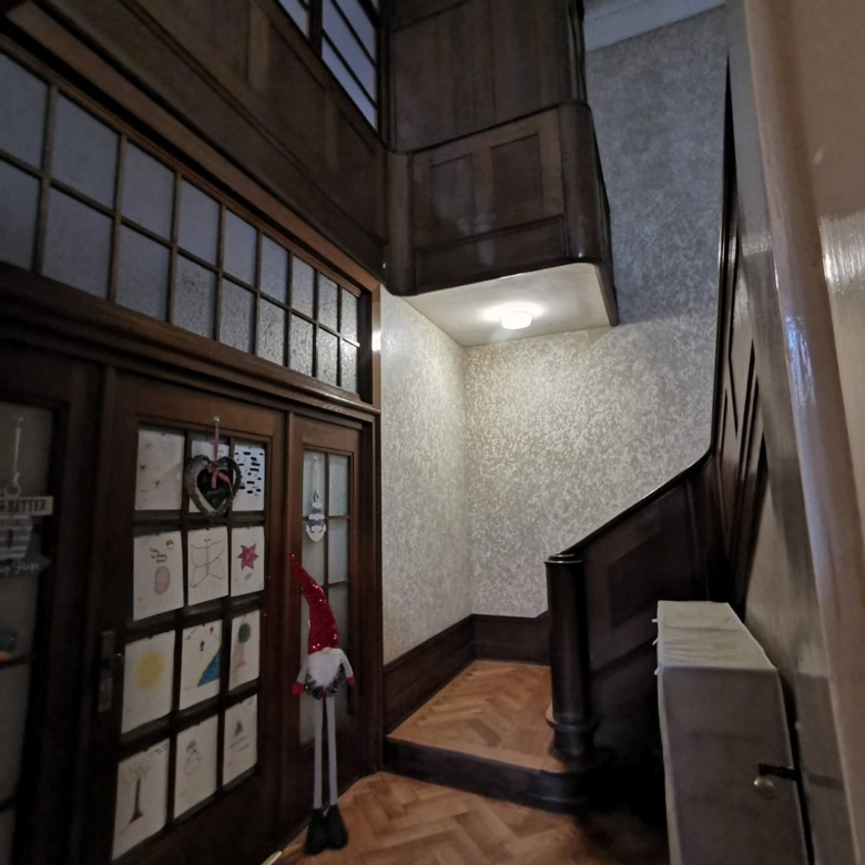Угловая лестница из тёмного дерева в прихожей с декоративными стенами и паркетным полом, уютное интерьерное решение.