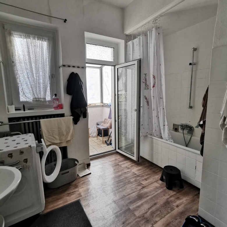 Душевая комната с ванной, окнами и балконным выходом, современный интерьер, деревянный пол, бытовая техника, удобное пространство для ежедневных процедур.