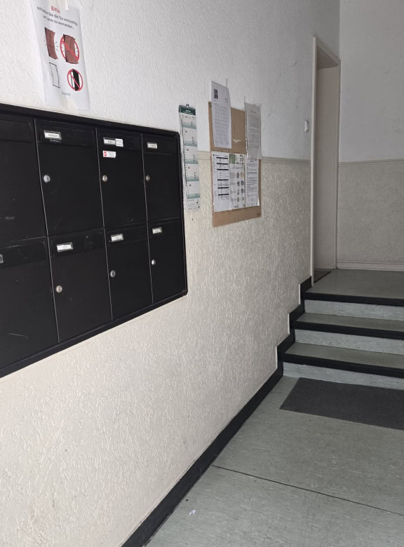 Schwarze Briefkästen in einem Mehrparteienhaus für Post- und Paketzustellung.