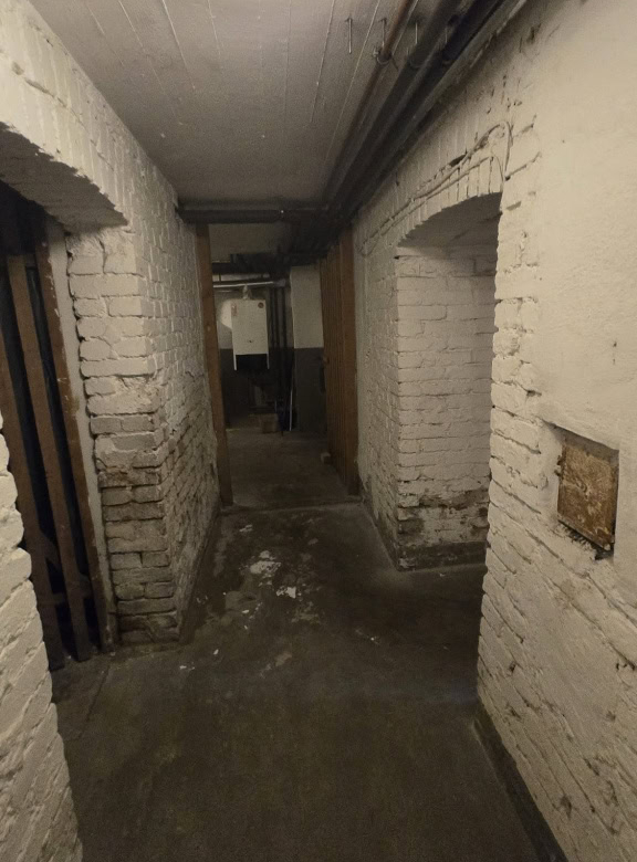 Rohbau-Flur mit sichtbaren Backsteinwänden und Deckenleuchte in einem historischen Gebäude, Unscharfe Aufnahme, Denkmalschutz, Renovierung, Gebäudesanierung, Altbauarchitektur.