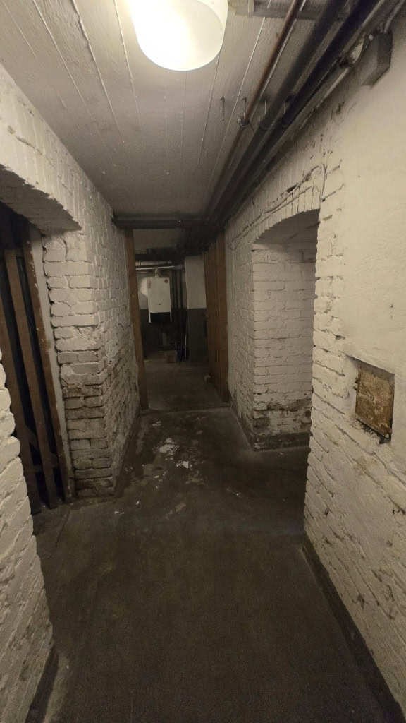 Rohbau-Flur mit sichtbaren Backsteinwänden und Deckenleuchte in einem historischen Gebäude, Unscharfe Aufnahme, Denkmalschutz, Renovierung, Gebäudesanierung, Altbauarchitektur.