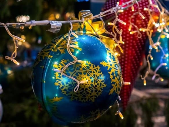 Blaue Weihnachtskugel mit goldenen Schneeflocken und Lichterkette, festliche Dekoration für Weihnachten, im Dunkeln beleuchtet, ideal für Weihnachtsbaum und festliche Stimmung.